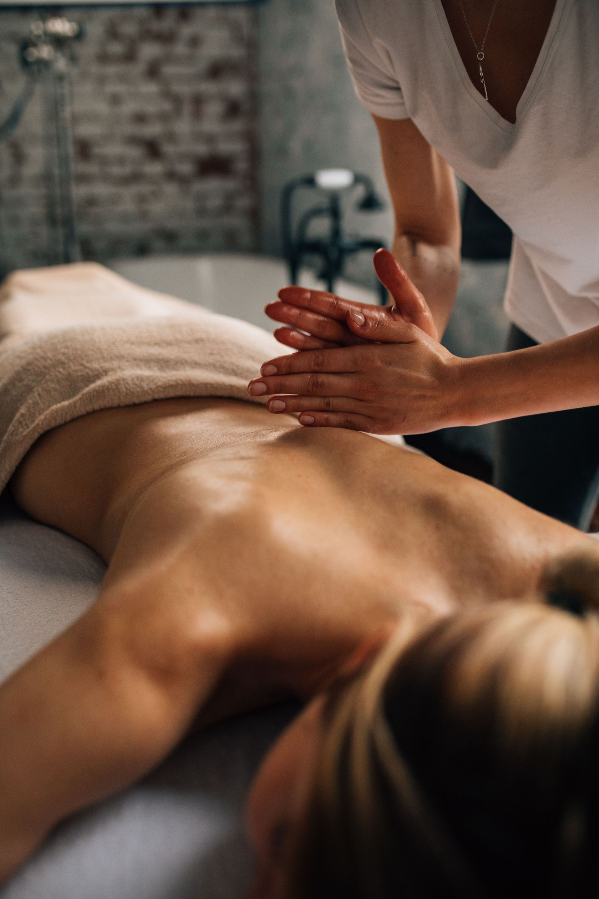 Relaxing indoor massage session with a masseuse providing rejuvenating body care.